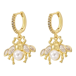 Close-up of golden bee earrings with white pearl abdomen and sparkling zircon wings