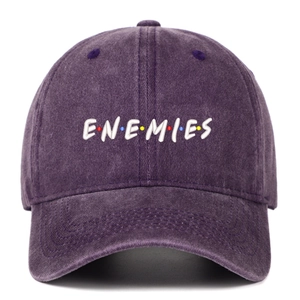 Close-up of white ENEMIES embroidery on a washed dark purple denim cotton baseball cap