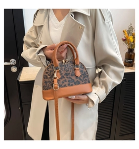 Chic leopard print shell bag with brown leather handles worn with a beige trench coat