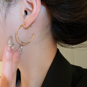 Vue de profil d'un mannequin portant une boucle d'oreille anneau dorée au fini brillant
