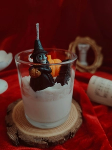 Detailed macro view of a Halloween candle with witch figurine and orange pumpkin topper