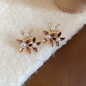Macro detail of 18K gold plated flower stud earrings with enamel petals and white pearls