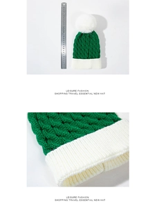 Detail of green knitted Christmas hat with white pompom and ruler for size measurement