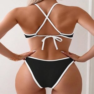 Detail of black bikini set with white piping showing back cross-tie closure and high-cut fit