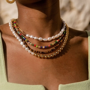 Close-up of layered bohemian necklaces featuring natural stones and pearls on a model