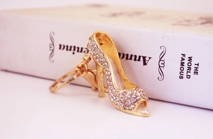 Detail of a golden high heel keychain with sparkling crystals leaning on a book