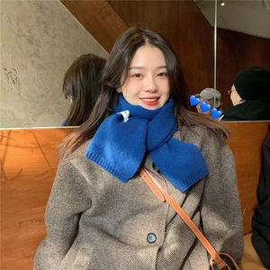 Close-up of blue knitted scarf on a woman in a soft-lit indoor cafe setting