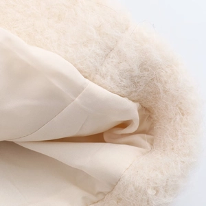 Detail shot of fluffy off-white plush fabric and smooth textile lining on a cozy women coat