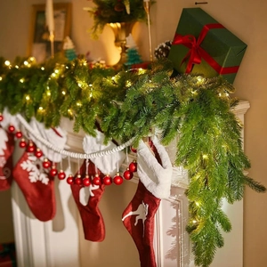 Illuminated artificial Christmas pine wreath with warm LED lights on a festive fireplace