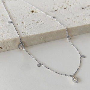Elegant silver tassel necklace with polished waterdrop pendants on minimalist stone base