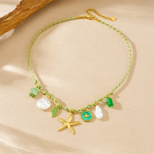 Detail of green woven cord necklace with gold starfish, leaf, and pearl pendants