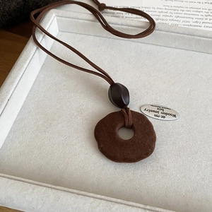 Detail view of vintage dark brown flocked pendant necklace on a soft grey display tray