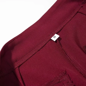 Macro detail of wine red fabric waistband with a white size S label and neat stitching