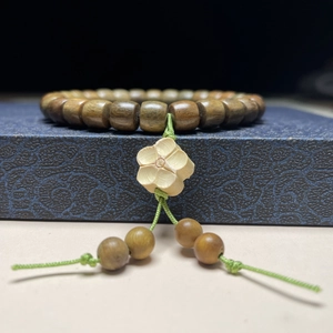 Detail eines Armbands aus Sandelholzperlen mit einem geschnitzten Pflaumenblüten-Anhänger