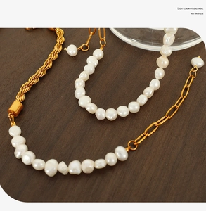 Detail of baroque pearl and gold twist chain necklace on a dark wood texture surface