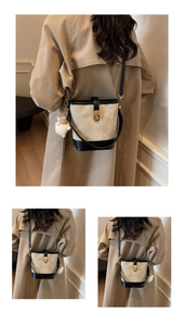 Contrast bucket bag in beige and black textured fabric shown on model with charm