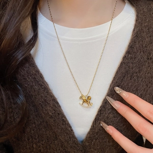 Detail of a gold horse necklace with tiger eye stone layered over a brown sweater