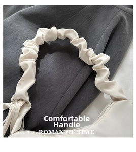 Detail of the white pleated cloud handle design on a minimalist matte leather shoulder bag