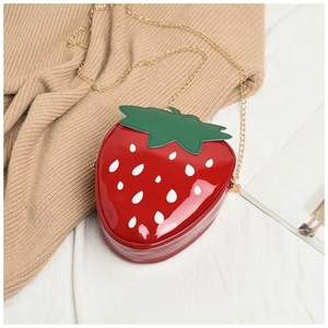 Macro detail of red strawberry bag with green leaves on knitted fabric background