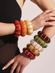 Detail of colorful resin bangles with gold lines worn on model arms in stylish layers