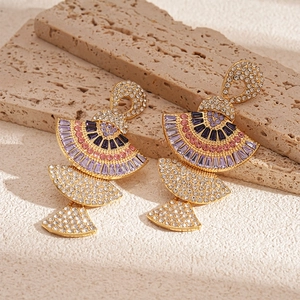 Detail of vintage tiered fan earrings with multi-colored crystals on a stone surface
