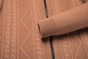 Detailed close-up of brown knit cardigan featuring ribbed cuffs and diamond cable patterns
