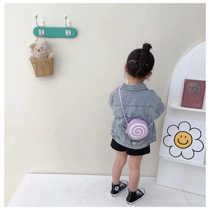 Girl wearing a blue denim jacket with graffiti print and a purple swirl crossbody bag