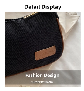 Close-up of black woven underarm bag with brown leather trim and embossed brand tag