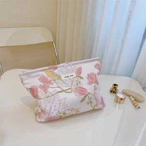 Detailansicht der rosa Jacquard-Kosmetiktasche mit Magnolien- und Vogelbestickung