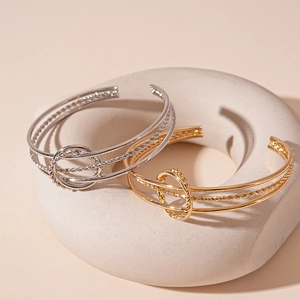 Three-layer geometric metal bangles in gold and silver finish with twisted ring detail