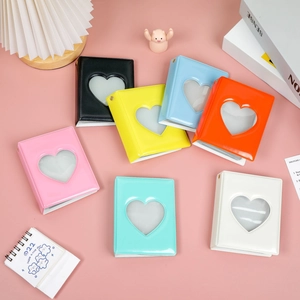 Mini photo albums with heart cutout cover in seven colors displayed on a pink desk