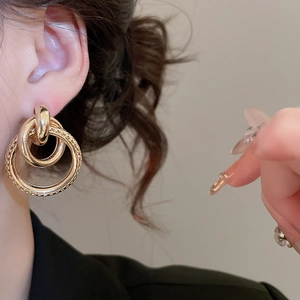 Gros plan d'un mannequin portant des boucles d'oreilles dorées circulaires texturées