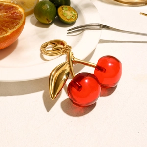 Nahaufnahme Kirsch-Schlüsselanhänger aus rotem Harz mit goldenem Blatt auf Marmor