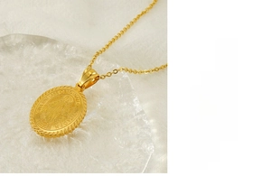 Macro detail of a golden stainless steel oval Virgin Mary pendant and chain necklace