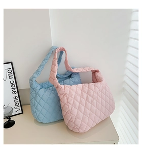 Macro detail of quilted puffy tote bags in light blue and pink soft nylon fabric