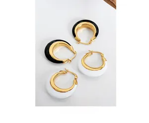Detailed view of thick retro hoop earrings with black and white enamel finishes