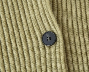 Close-up of mustard green ribbed knit sweater featuring a matte black button detail