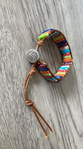 Close-up of handmade bohemian bracelet with colorful emperor stones and tree of life button