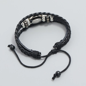 Close-up of woven black leather soccer bracelet with silver metal charm and adjustable cord