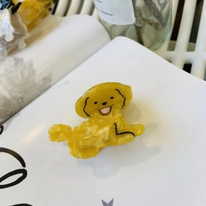 Cute yellow dachshund dog hair claw clip made of glossy acetate on a book page