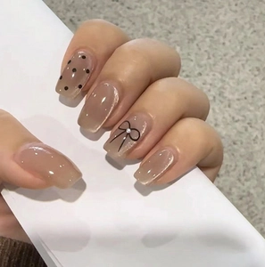 Macro view of square press-on nails with black bow, pearls and polka dot patterns