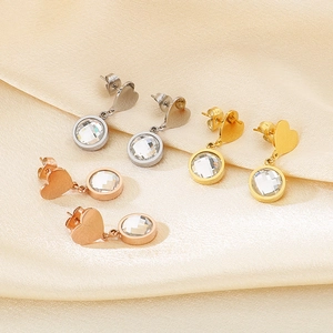 Detailed view of heart-shaped earrings with clear round cubic zirconia on silk fabric