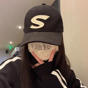 Detail view of a black cotton baseball cap with a white embroidered letter S