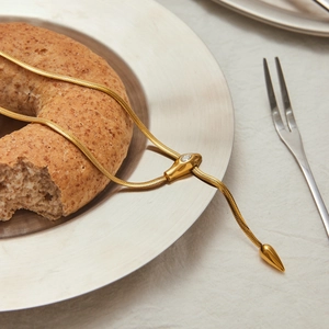 Detaillierte Nahaufnahme der goldenen Schlangenkette mit Zirkonia auf stilvollem Gedeck