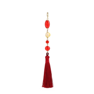 Detailed macro view of red tassel pendant with golden lobster clasp and beads