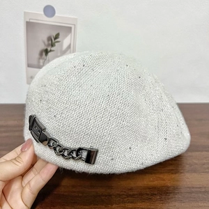 Close-up of light gray knit beret with shimmering sequins and metal chain detail