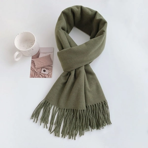 Detailed view of an army green tassel scarf with a ceramic mug on a white background