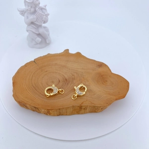 Gold plated lobster clasp with sparkling zircon stones on a rustic wooden display tray