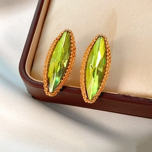 Close-up of marquise-cut yellow-green crystal earrings with golden beaded edges