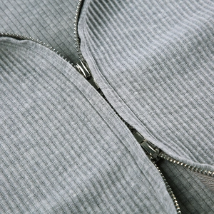 Detaillierte Nahaufnahme von grauem Rippstrick und silbernem Metallreißverschluss am Hoodie